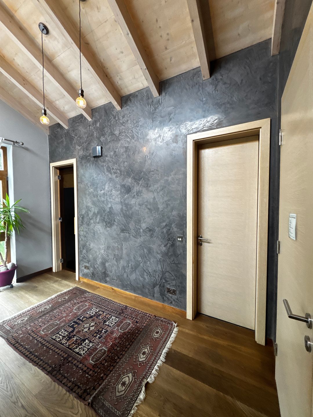 A hallway wall in grey Spatula Stucchi with a polished, marble-like sheen