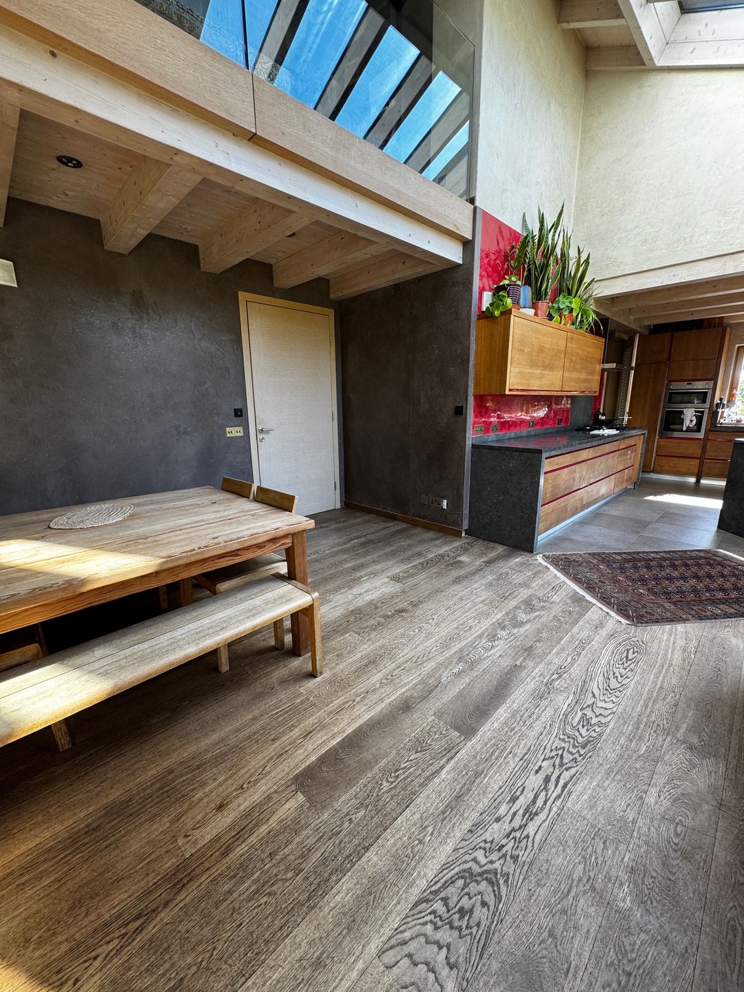 Living and dining space with dark plaster walls and a red kitchen splashback