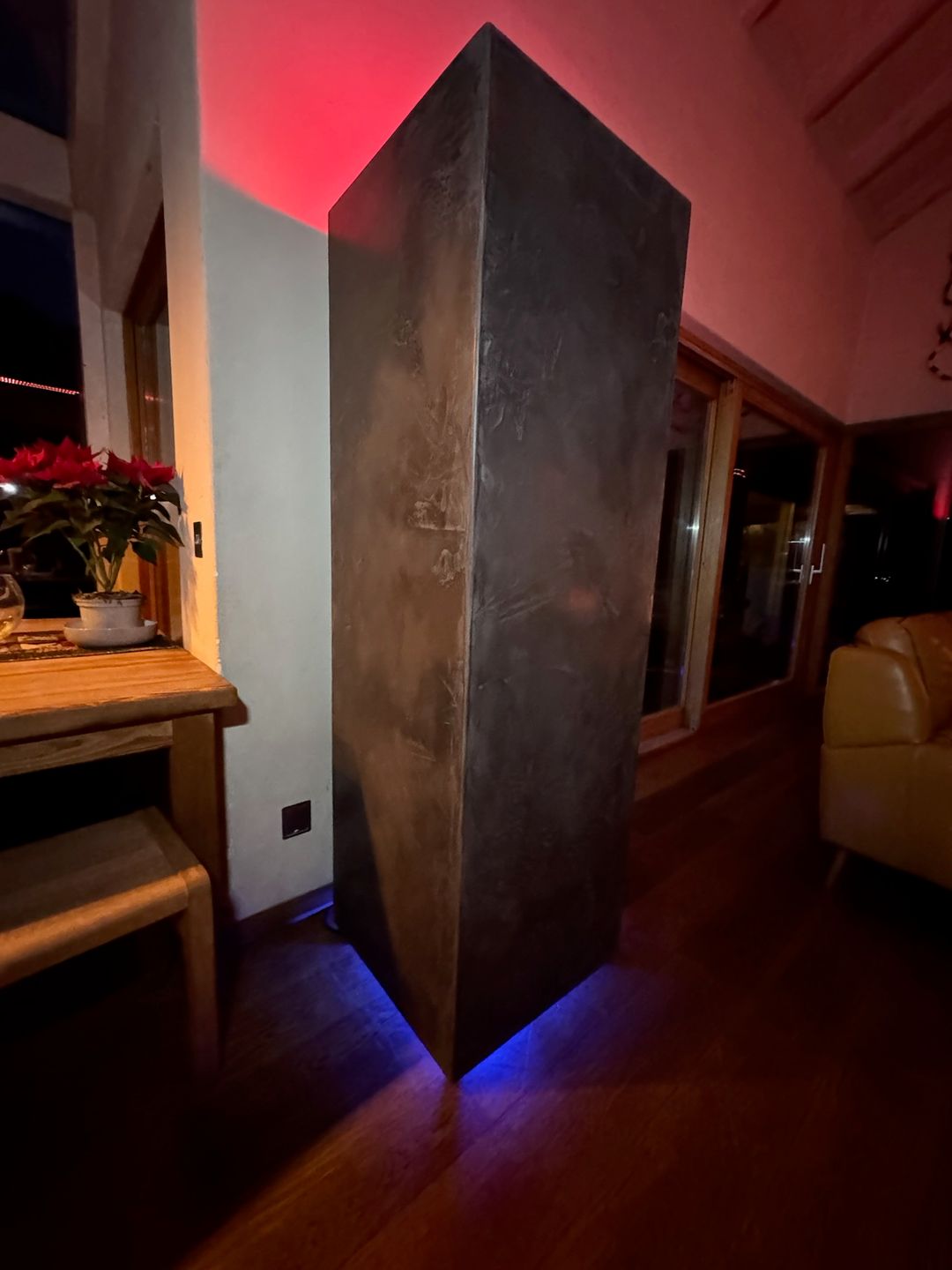 The GLO Tower standing in a room, its hand-finished dark plaster surface catching the light