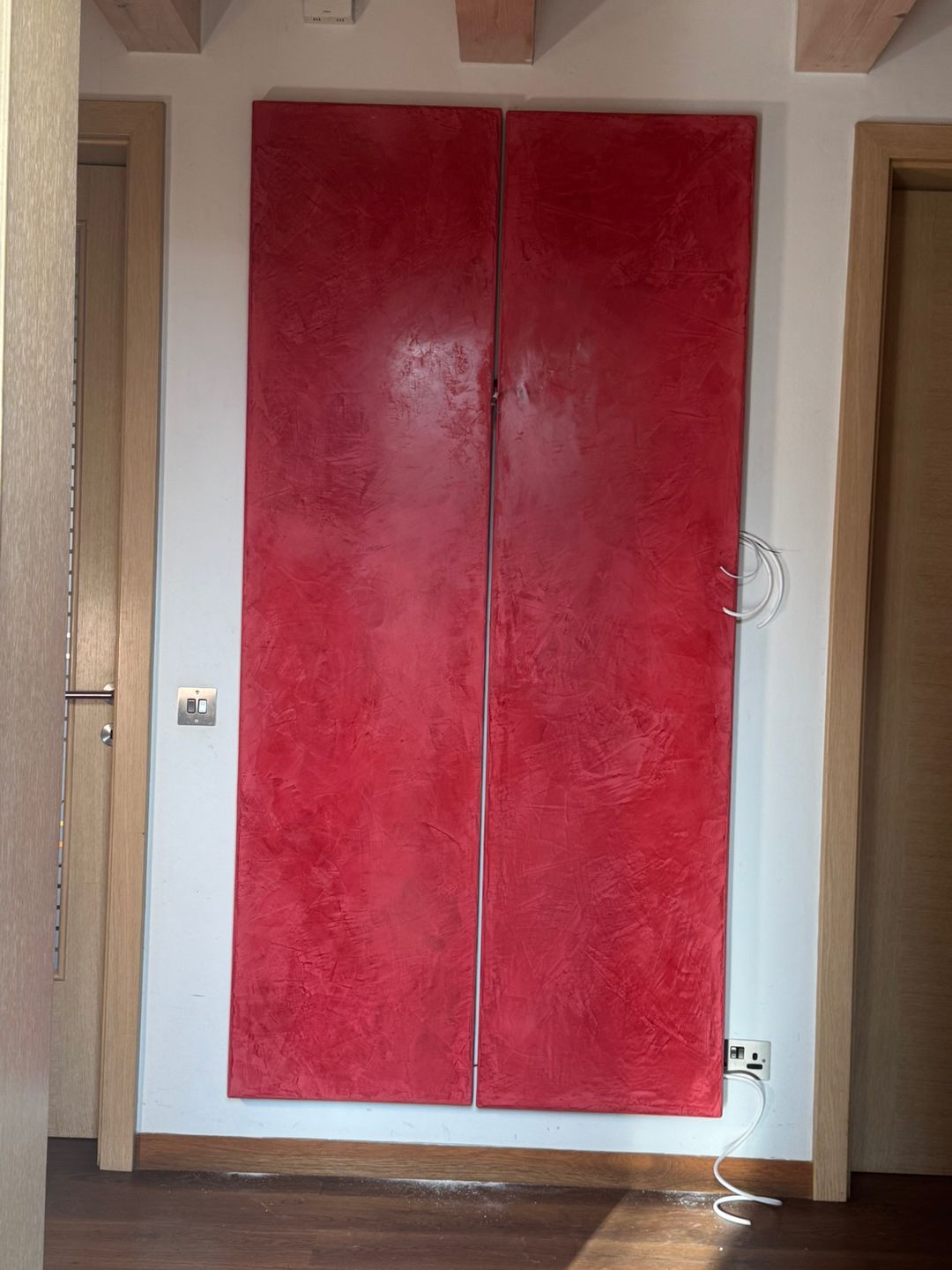Two large red textured panels installed on a hallway wall